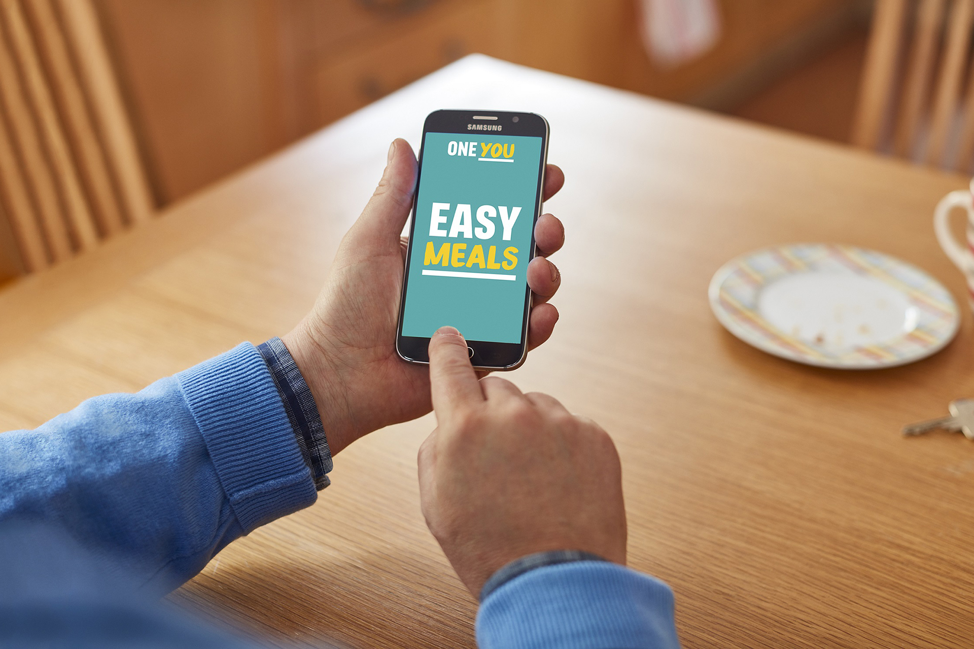 Two hands holding a phone about to use the easy meals app 