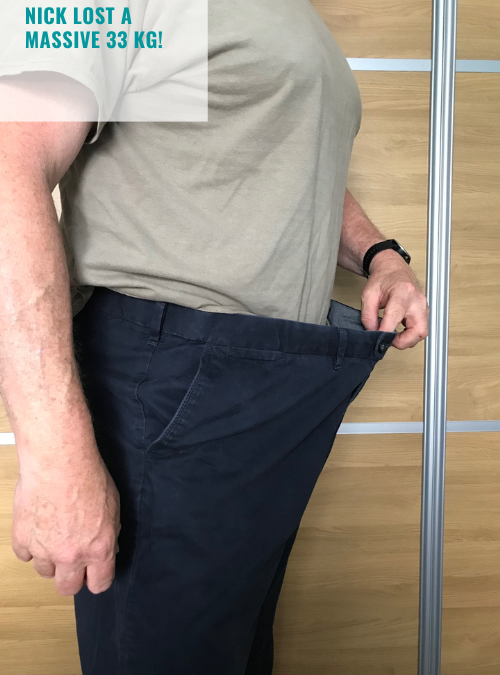 A man standing on the side holding out his trousers to show how much weight he has lost
