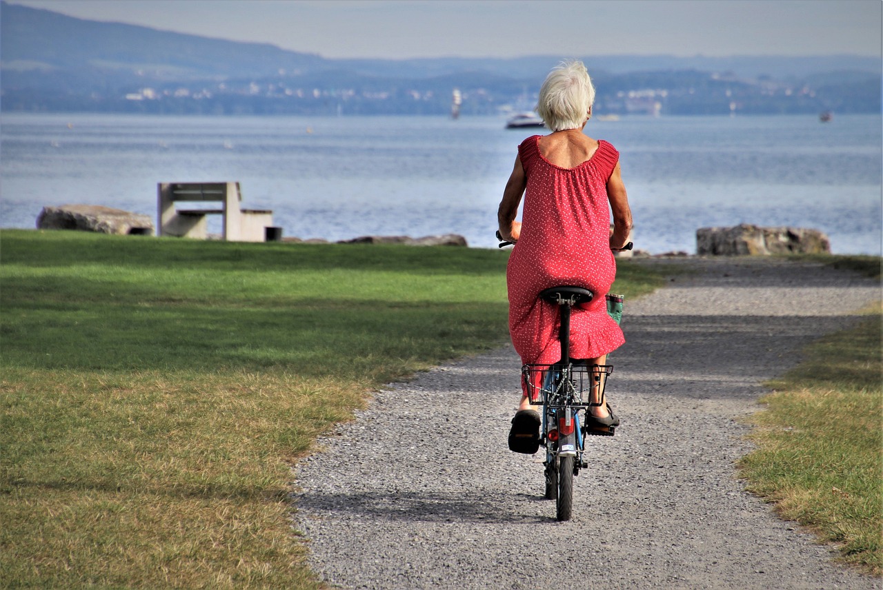 Older Female cycling with the sea view in the background