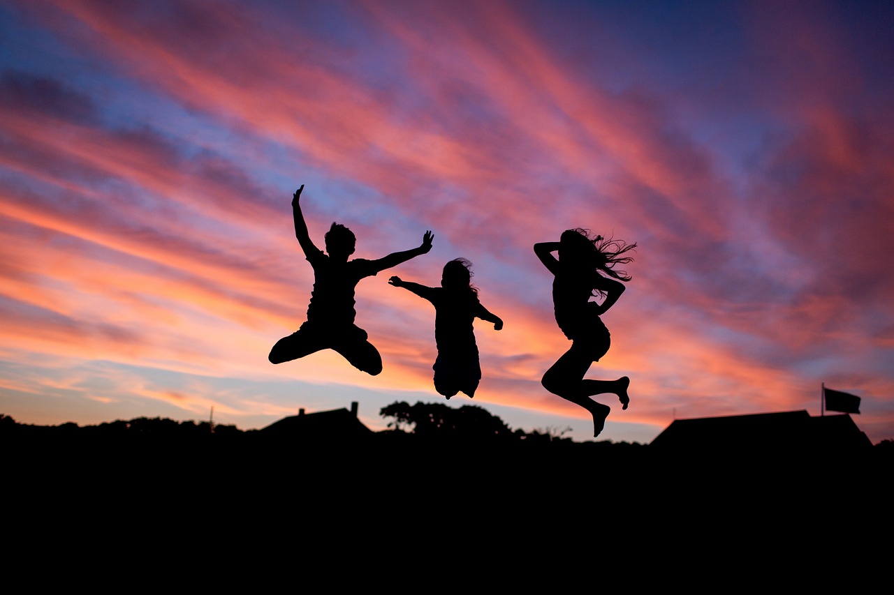 people jumping with the sunset behind them