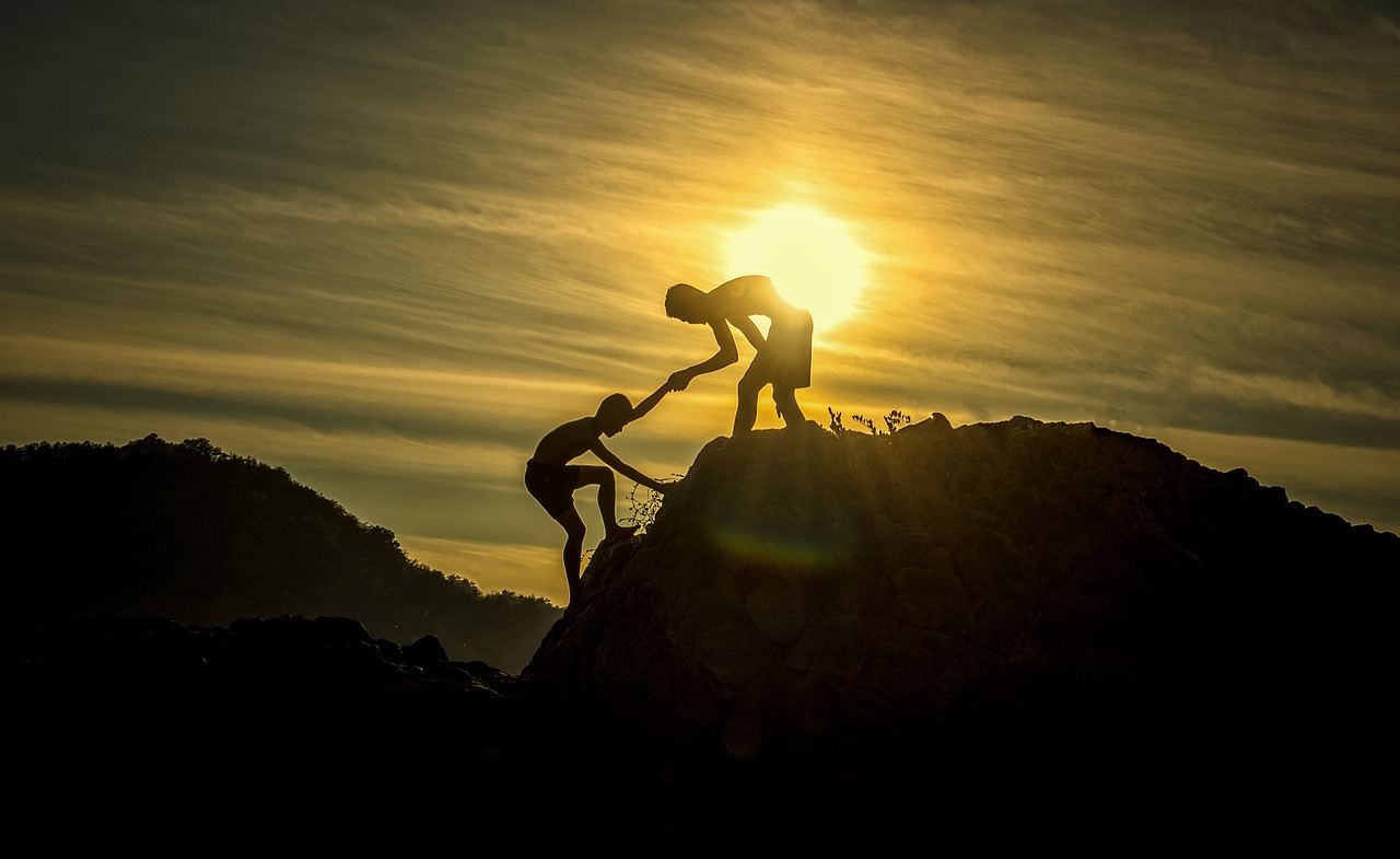 a person helping another get up a hill - supporting each other